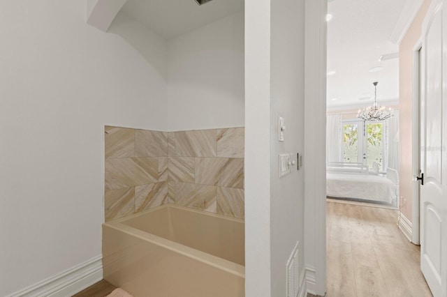 bathroom featuring a chandelier, wood finished floors, and baseboards