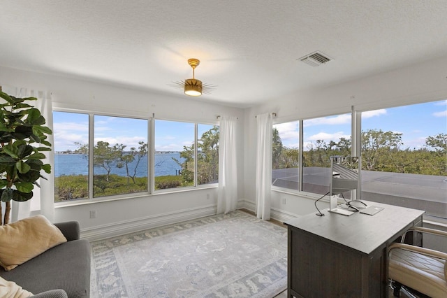 sunroom featuring a water view