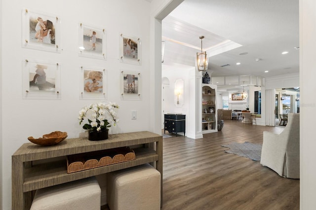 corridor with wood finished floors, crown molding, recessed lighting, and a chandelier