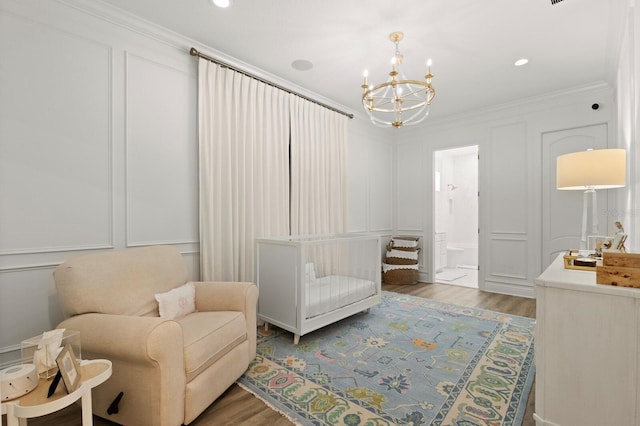 living area featuring a decorative wall, a chandelier, wood finished floors, and ornamental molding