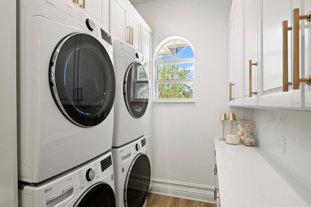laundry room featuring stacked washer / drying machine, cabinet space, washing machine and dryer, and baseboards