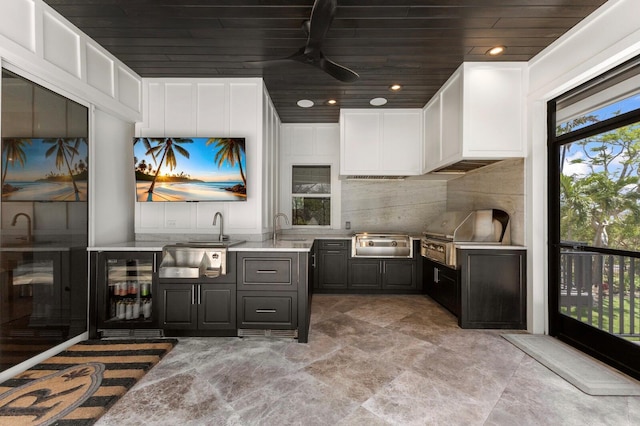 kitchen with wood ceiling, beverage cooler, a sink, light countertops, and ceiling fan