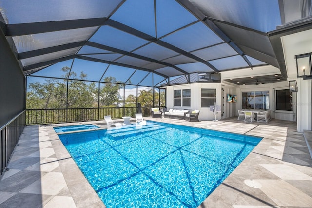 view of swimming pool featuring a patio, outdoor lounge area, a pool with connected hot tub, a ceiling fan, and a lanai