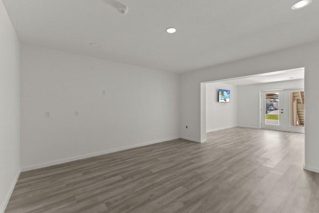 empty room featuring wood finished floors, recessed lighting, baseboards, and french doors