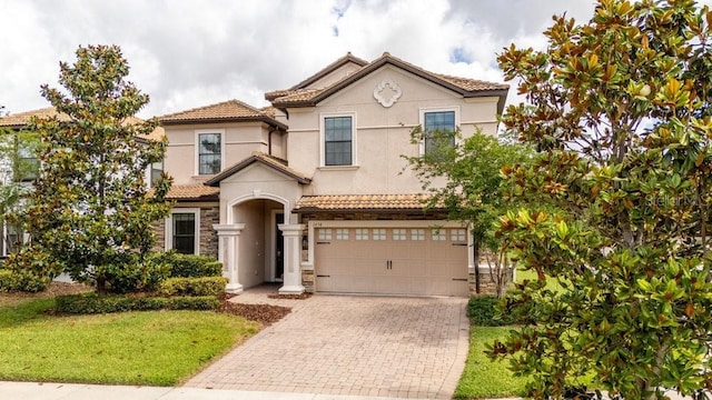 1450 Rolling Fairway Dr, Davenport, FL 33896 - mediterranean / spanish-style house featuring decorative driveway, an attached garage, stucco siding, stone siding, and a tile roof