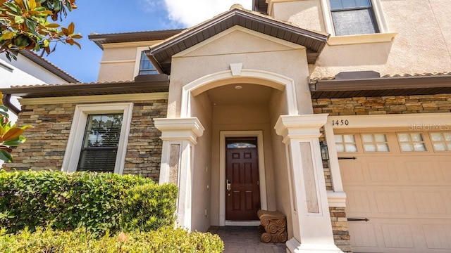 1450 Rolling Fairway Dr, Davenport, FL 33896 - view of exterior entry with stone siding, a garage, and stucco siding