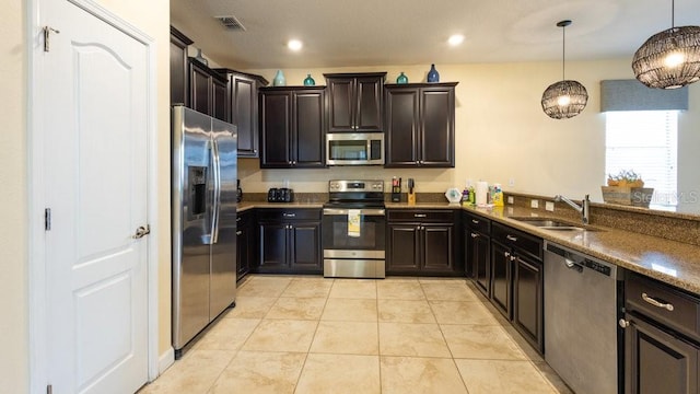 1450 Rolling Fairway Dr, Davenport, FL 33896 - kitchen with appliances with stainless steel finishes, a sink, light tile patterned flooring, hanging light fixtures, and stone countertops