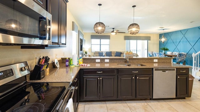 1450 Rolling Fairway Dr, Davenport, FL 33896 - kitchen featuring stainless steel appliances, a sink, ceiling fan, a peninsula, and light stone countertops