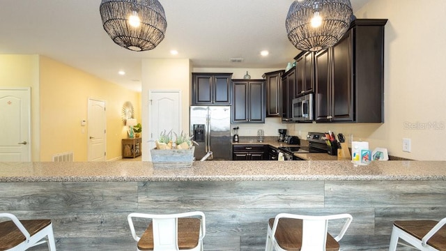 1450 Rolling Fairway Dr, Davenport, FL 33896 - kitchen featuring stainless steel appliances, dark brown cabinetry, light stone countertops, a breakfast bar area, and recessed lighting