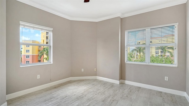 empty room featuring ornamental molding, baseboards, ceiling fan, and light wood-style flooring