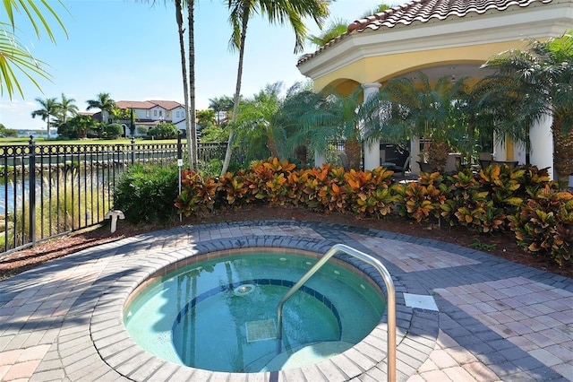 view of pool with fence, a hot tub, and a water view
