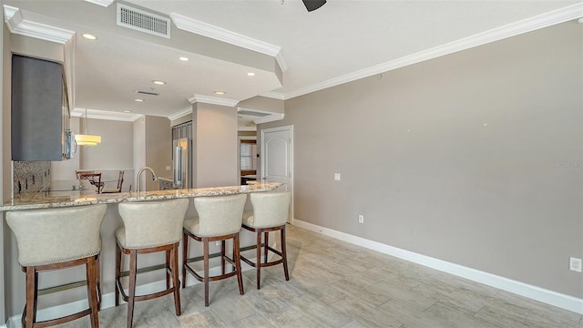 610 Riviera Dunes Way Unit 308, Palmetto, FL 34221 - kitchen with light stone counters, baseboards, crown molding, a peninsula, and recessed lighting