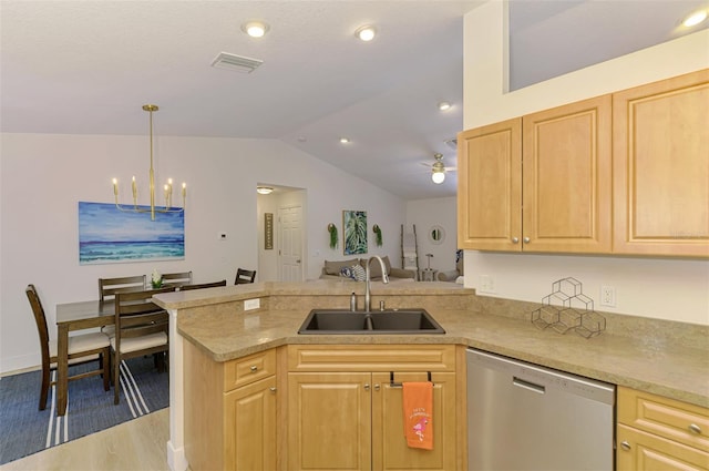 kitchen with stainless steel dishwasher, a sink, vaulted ceiling, a peninsula, and light brown cabinets