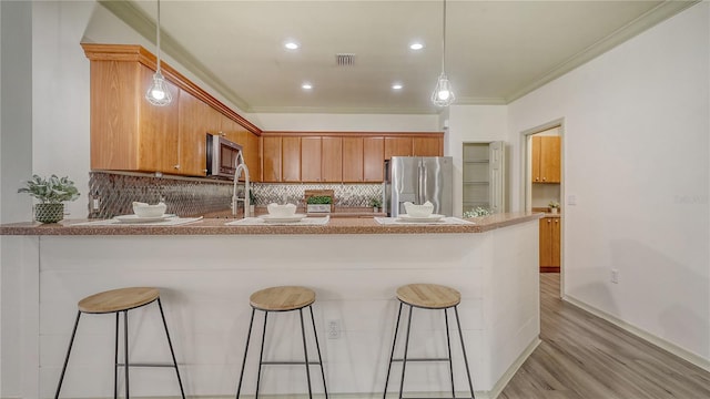 203 28th St W, Palmetto, FL 34221 - kitchen featuring stainless steel appliances, a peninsula, light wood-style flooring, ornamental molding, and backsplash