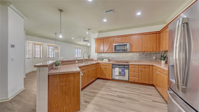 203 28th St W, Palmetto, FL 34221 - kitchen featuring stainless steel appliances, a sink, a peninsula, light wood-style floors, and tasteful backsplash