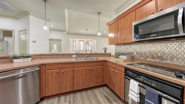 203 28th St W, Palmetto, FL 34221 - kitchen with stainless steel appliances, a sink, light wood-style flooring, hanging light fixtures, and ornamental molding