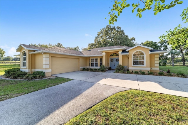 single story home with stucco siding, a garage, driveway, and a front yard