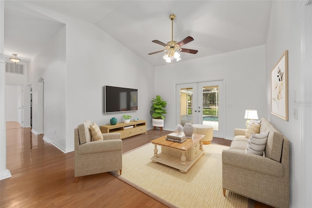 living area featuring french doors, ceiling fan, light wood-style flooring, high vaulted ceiling, and baseboards