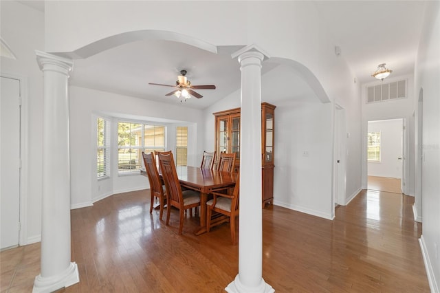 dining space with arched walkways, ornate columns, a ceiling fan, light wood-style flooring, and vaulted ceiling