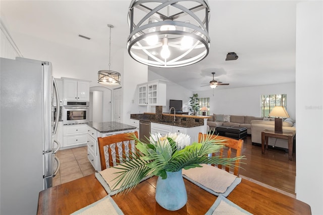 dining room featuring a ceiling fan, lofted ceiling, a chandelier, and light wood-style flooring