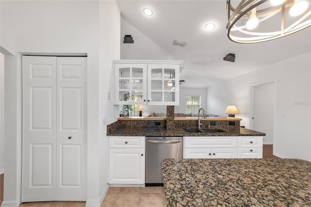 kitchen with dishwasher, a sink, dark stone counters, white cabinets, and a peninsula