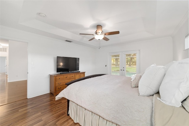 bedroom featuring a raised ceiling, french doors, access to exterior, wood finished floors, and crown molding