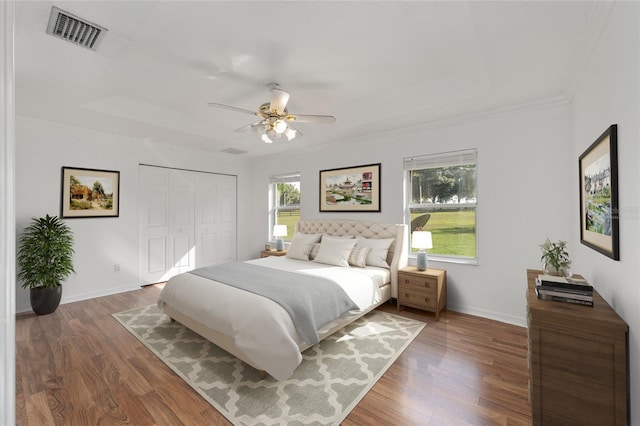 bedroom featuring wood finished floors, crown molding, a closet, a ceiling fan, and baseboards