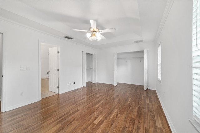 unfurnished bedroom featuring wood finished floors, ornamental molding, a tray ceiling, baseboards, and a ceiling fan