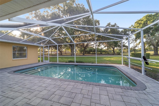 outdoor pool with a lawn, glass enclosure, and a patio area