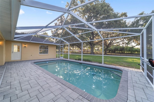 swimming pool featuring a patio area, a lawn, and glass enclosure