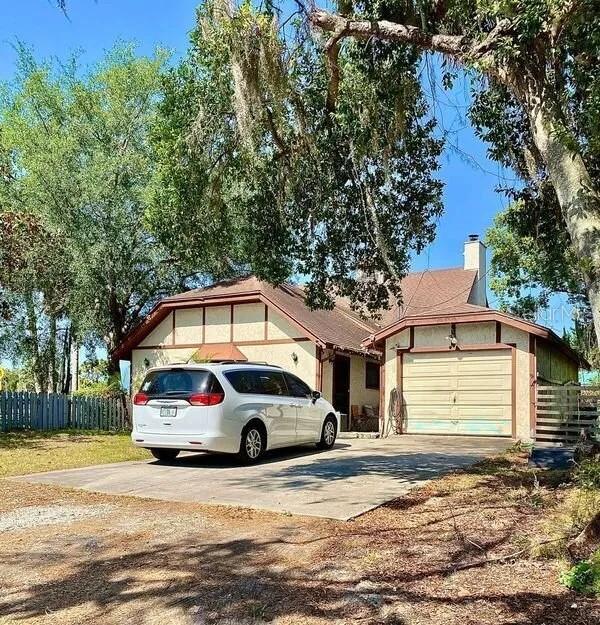 ranch-style home with concrete driveway, fence, a chimney, and an attached garage