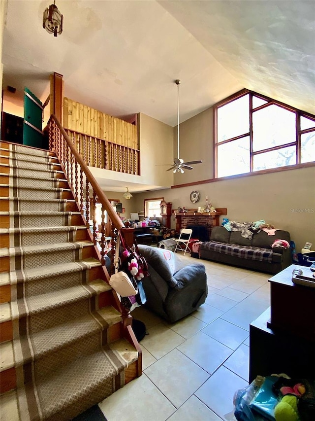tiled living area featuring vaulted ceiling, ceiling fan, and stairway