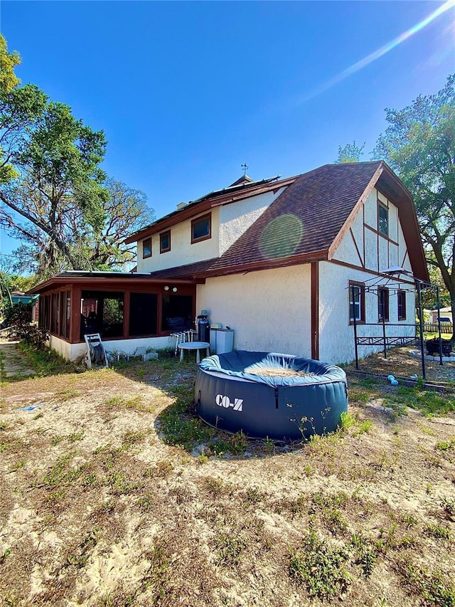 back of house featuring a covered pool and stucco siding