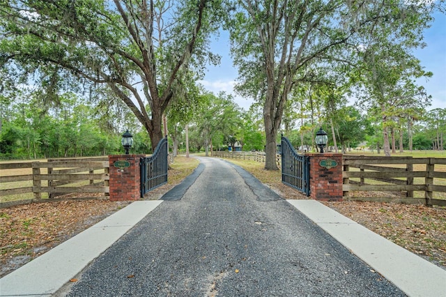 140 Cowpen Ln, Sarasota, FL 34240 - view of asphalt driveway with a gate, street lighting, and a gated entry