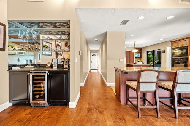140 Cowpen Ln, Sarasota, FL 34240 - indoor wet bar with wine cooler, black appliances, wood finished floors, baseboards, and recessed lighting