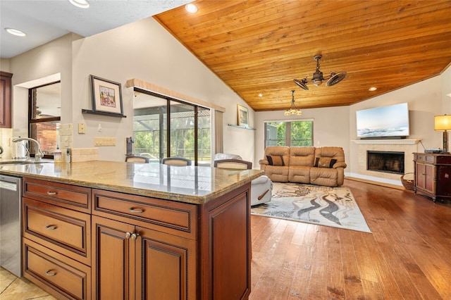 140 Cowpen Ln, Sarasota, FL 34240 - kitchen featuring a sink, dishwasher, light stone countertops, a fireplace with raised hearth, and wood finished floors