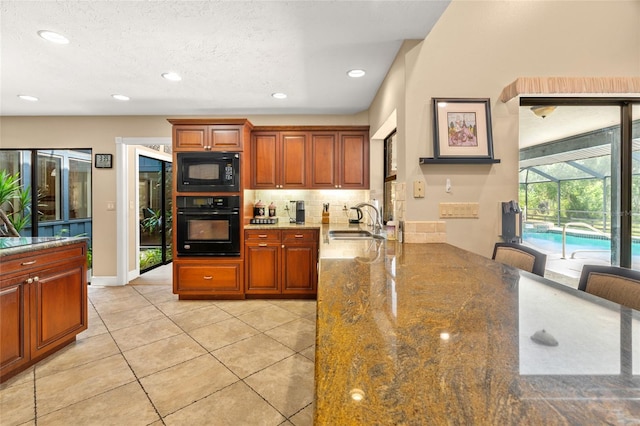140 Cowpen Ln, Sarasota, FL 34240 - kitchen with black appliances, a sink, decorative backsplash, light tile patterned flooring, and stone countertops