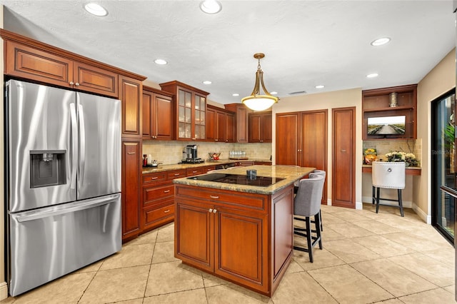 140 Cowpen Ln, Sarasota, FL 34240 - kitchen with stainless steel refrigerator with ice dispenser, black electric stovetop, light tile patterned flooring, tasteful backsplash, and light stone countertops