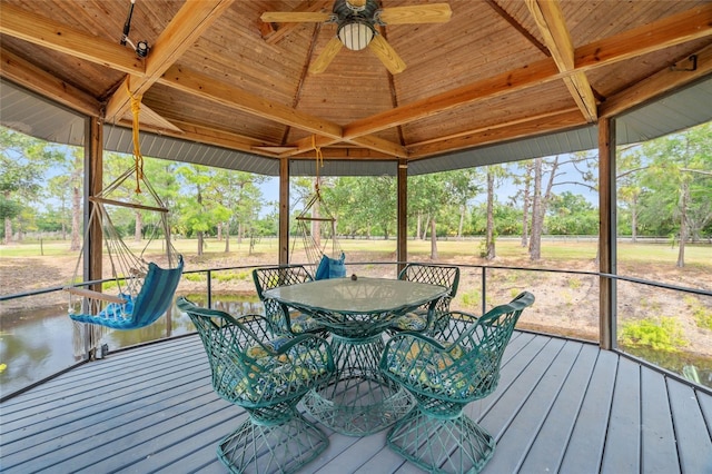 140 Cowpen Ln, Sarasota, FL 34240 - sunroom featuring a ceiling fan, view of scattered trees, outdoor dining area, and beamed ceiling