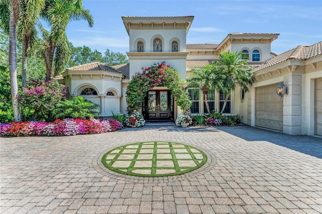 mediterranean / spanish home with french doors, curved driveway, and stucco siding