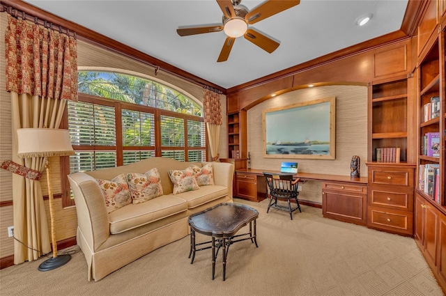 living area featuring light carpet, wooden walls, a ceiling fan, ornamental molding, and built in features