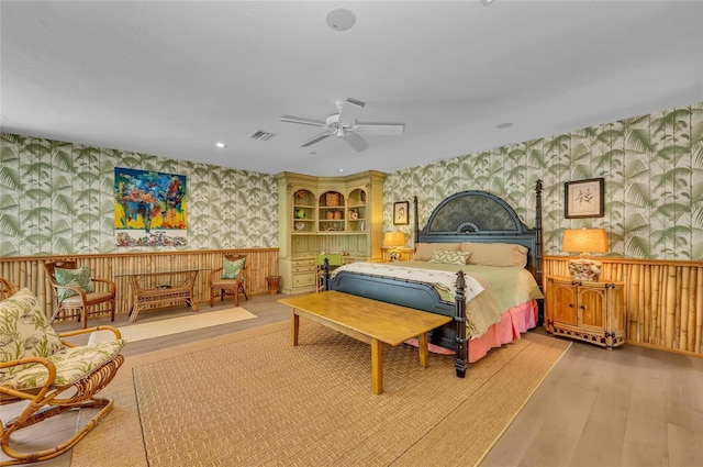 bedroom with wallpapered walls, wood finished floors, wainscoting, recessed lighting, and ceiling fan