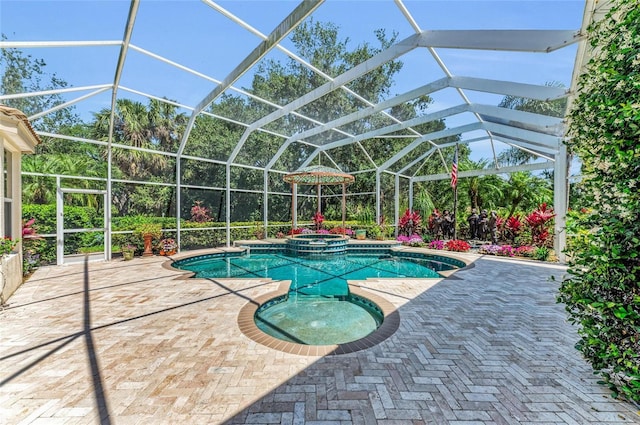 view of swimming pool with a pool with connected hot tub, a patio area, and glass enclosure