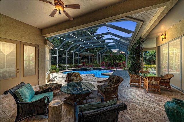 view of pool with ceiling fan, a patio area, a pool with connected hot tub, and glass enclosure