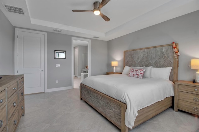 10414 Spring Tide Way, Parrish, FL 34219 - bedroom with a tray ceiling, ensuite bathroom, a ceiling fan, and baseboards