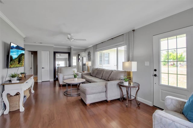living area with ornamental molding, wood finished floors, ceiling fan, and baseboards