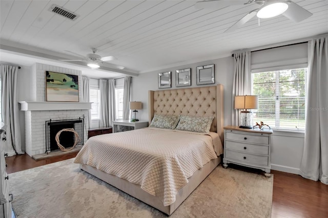 bedroom featuring multiple windows, wood finished floors, a fireplace, and wooden ceiling