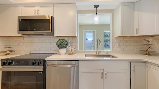 445 Matisse Cir S Unit 445, Nokomis, FL 34275 - kitchen with appliances with stainless steel finishes, a sink, white cabinets, decorative backsplash, and hanging light fixtures