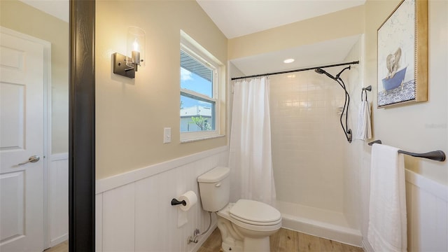 445 Matisse Cir S Unit 445, Nokomis, FL 34275 - bathroom with toilet, a wainscoted wall, a tile shower, and wood finished floors