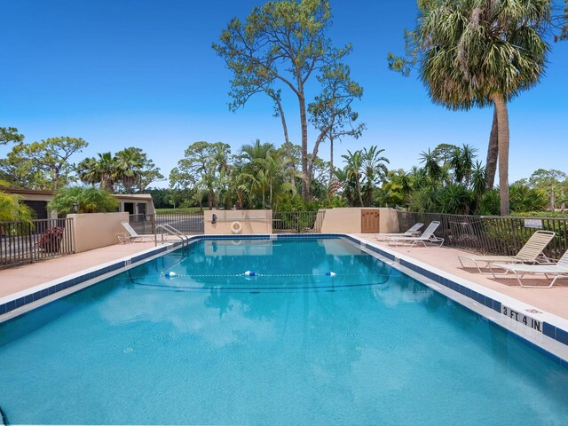 community pool with fence and a patio area